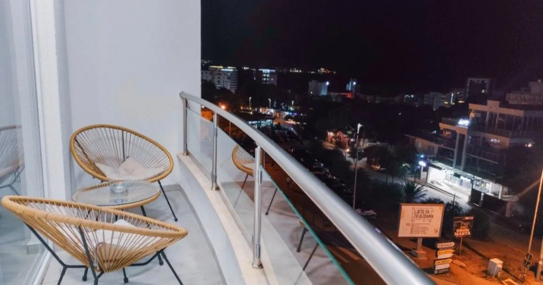 Furnished balcony with seating set and city view at night.