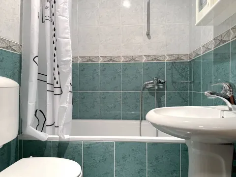 Smaller bathroom with a bathtub, washbasin, and toilet bowl tiled with ceramic tiles. - image 8