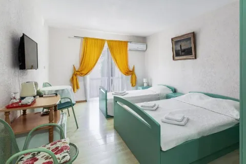 Spavaća soba sa dva kreveta, TV-om i stolom sa stolicama. - image 6