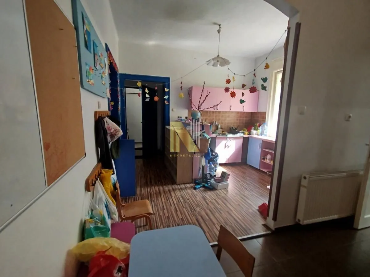 Small kitchen with pink cabinets and a dining table in the hallway.