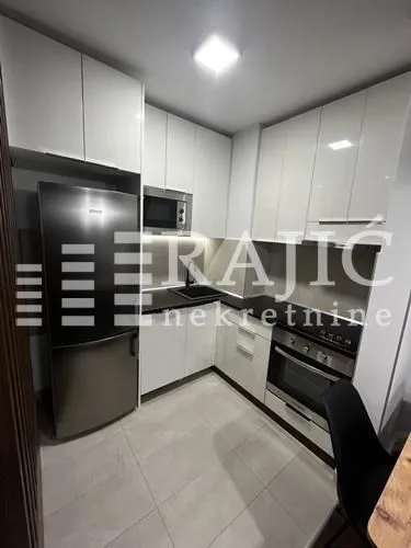 Modern white kitchen with built-in appliances and a refrigerator.