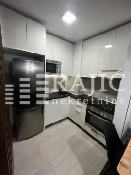 Modern white kitchen with built-in appliances and a refrigerator. - image 6