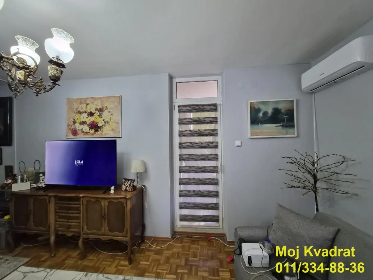 Dnevna soba sa garniturom, televizorom i klima uređajem.
