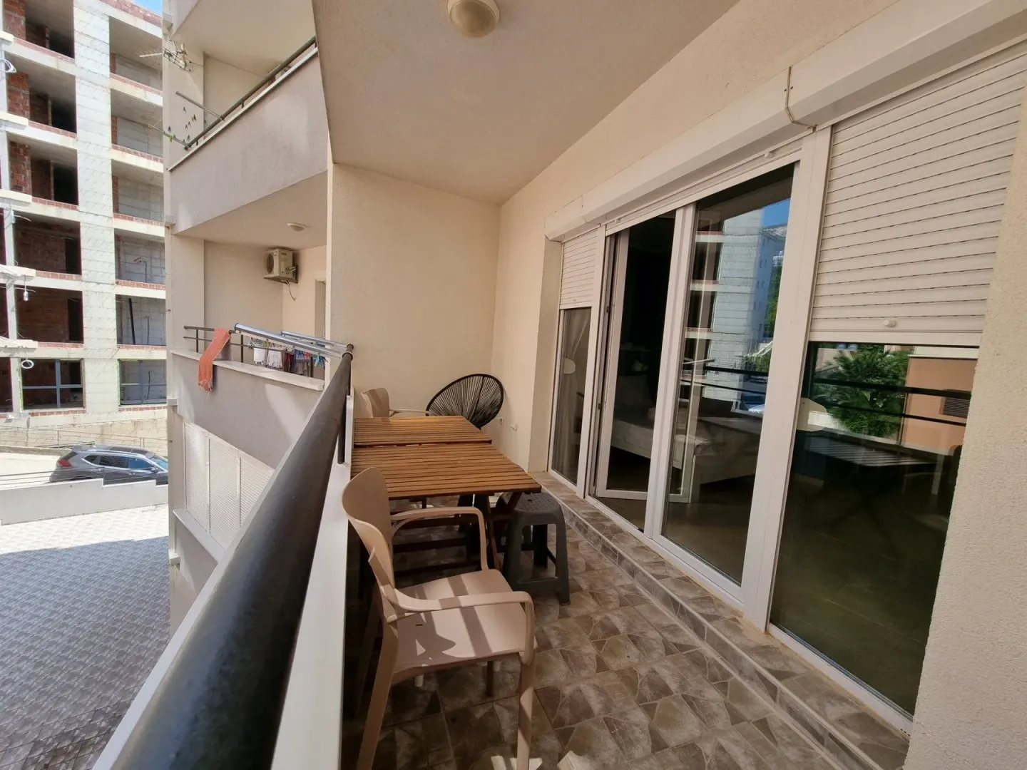 Furnished balcony with a table and chairs and a view of surrounding buildings.