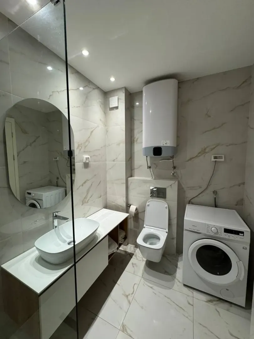 Modern bathroom with a washing machine and a large mirror.