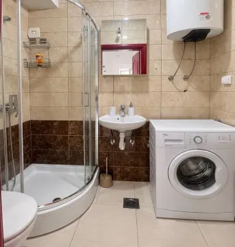 Small bathroom with a shower cabin, washbasin, and washing machine. - image 12