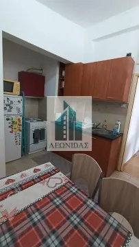Small kitchen with wooden cabinetry and a dining table in the foreground. - image 6