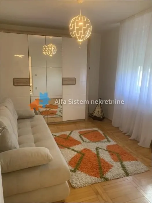 Dnevna soba sa garniturom za sedenje, velikim plakarom i tepihom.