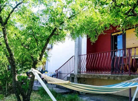 Dvorište kuće sa terasom, drvećem i ležaljkom. - image 7