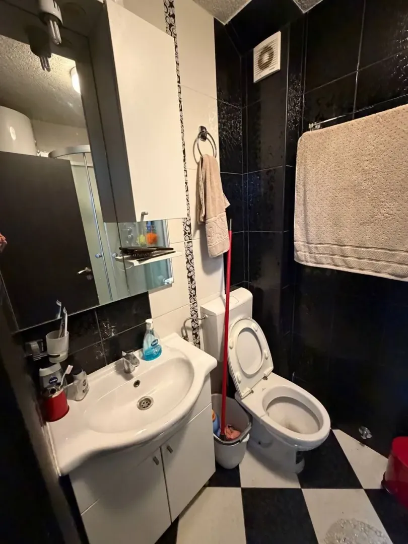 Manje kupatilo sa umivaonikom, WC šoljom i crno-bijelim pločicama.