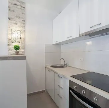 Small white kitchen with a built-in oven and cooktop. - image 2