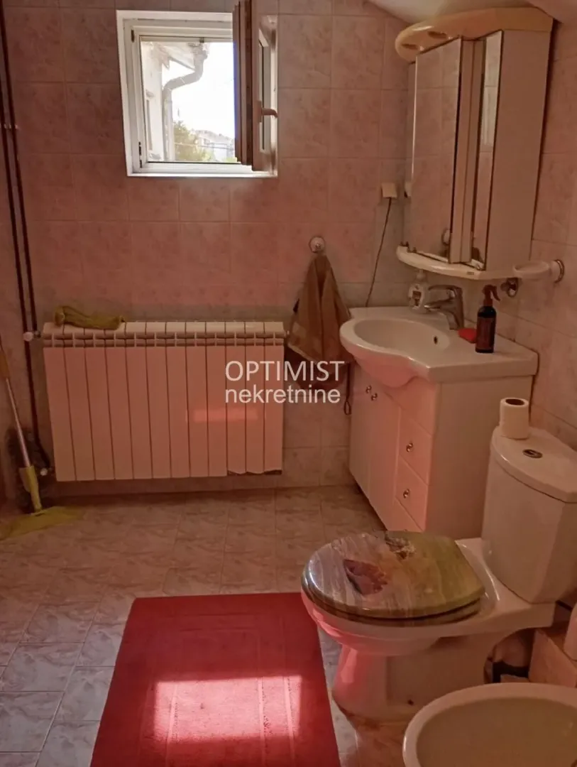 Bathroom with a washbasin, toilet, bidet, and a window.