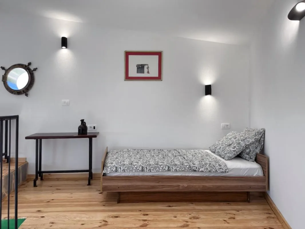 Manja spavaća soba sa krevetom i drvenim podom.