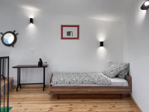Manja spavaća soba sa krevetom i drvenim podom. - image 8
