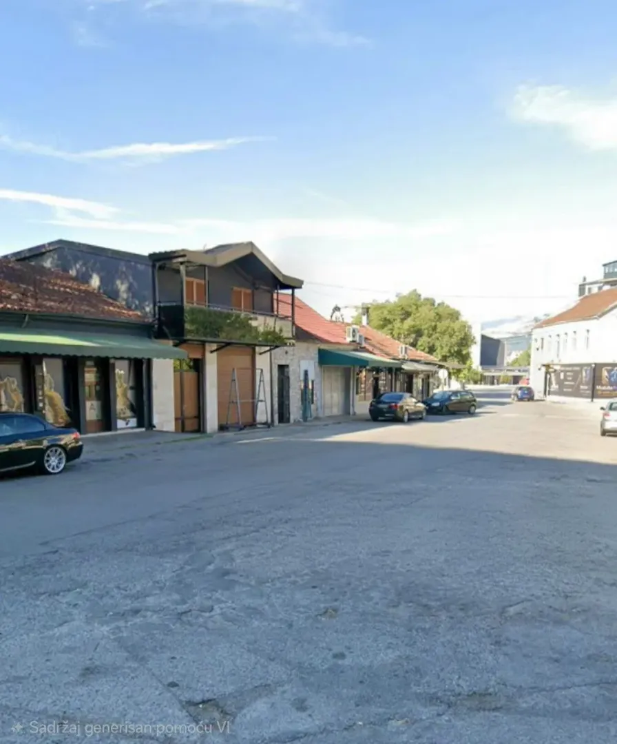 View of the street with commercial spaces and parked cars.