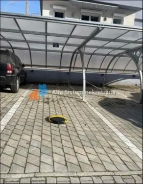 Natkriveni parking prostor sa popločanim podom i parkiranim automobilom. - image 17