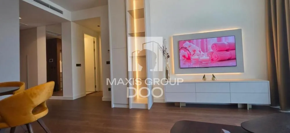 Living room with a TV, white furniture, and wooden flooring.