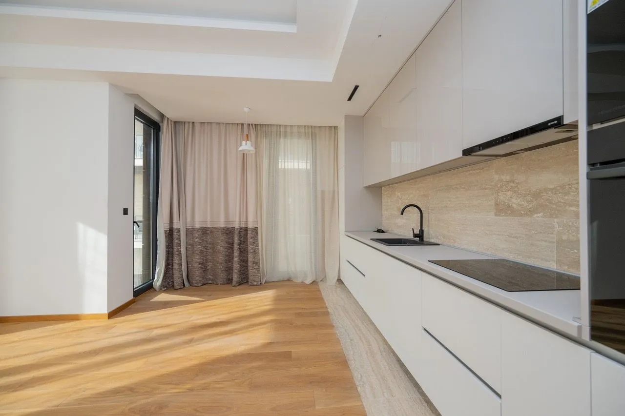 Modern white kitchen with built-in appliances and dining area.
