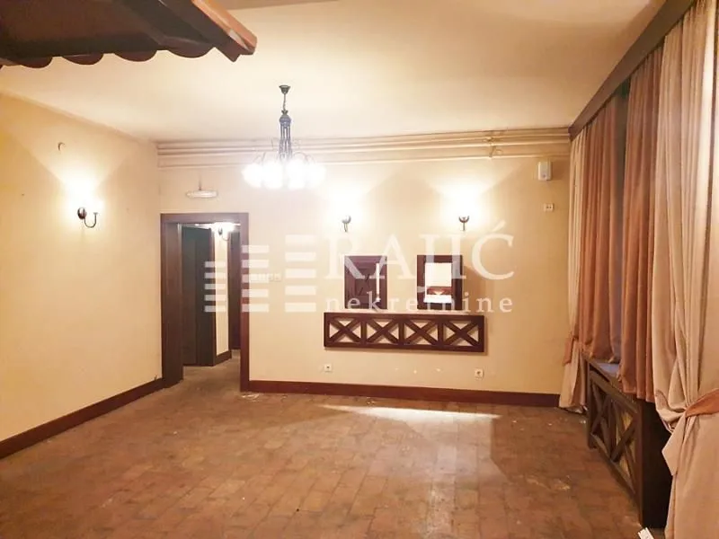 Spacious empty room with wooden wall features and a large window with curtains.