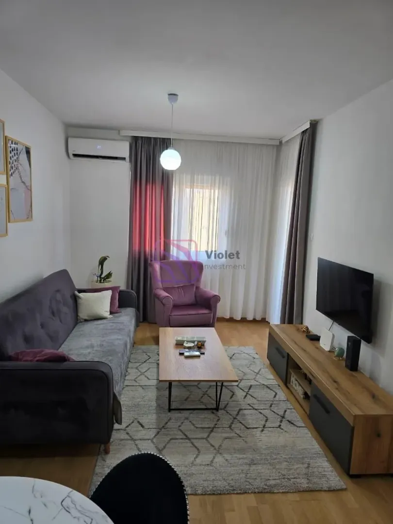Dnevna soba sa garniturom, TV-om i izlazom na terasu.