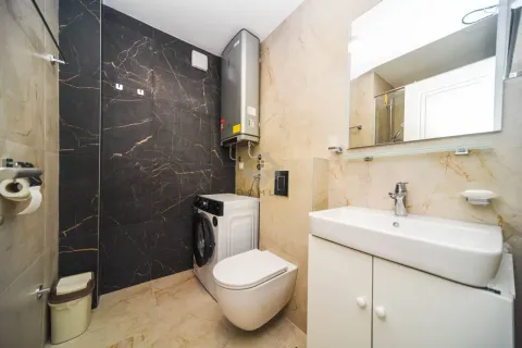 Modernly equipped bathroom with a washbasin, toilet, and washing machine. - image 8