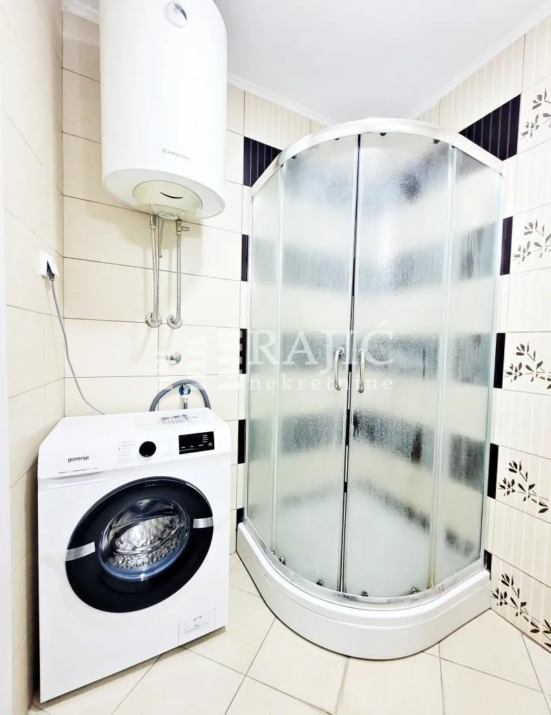 Bathroom with a shower cabin, water heater and washing machine.