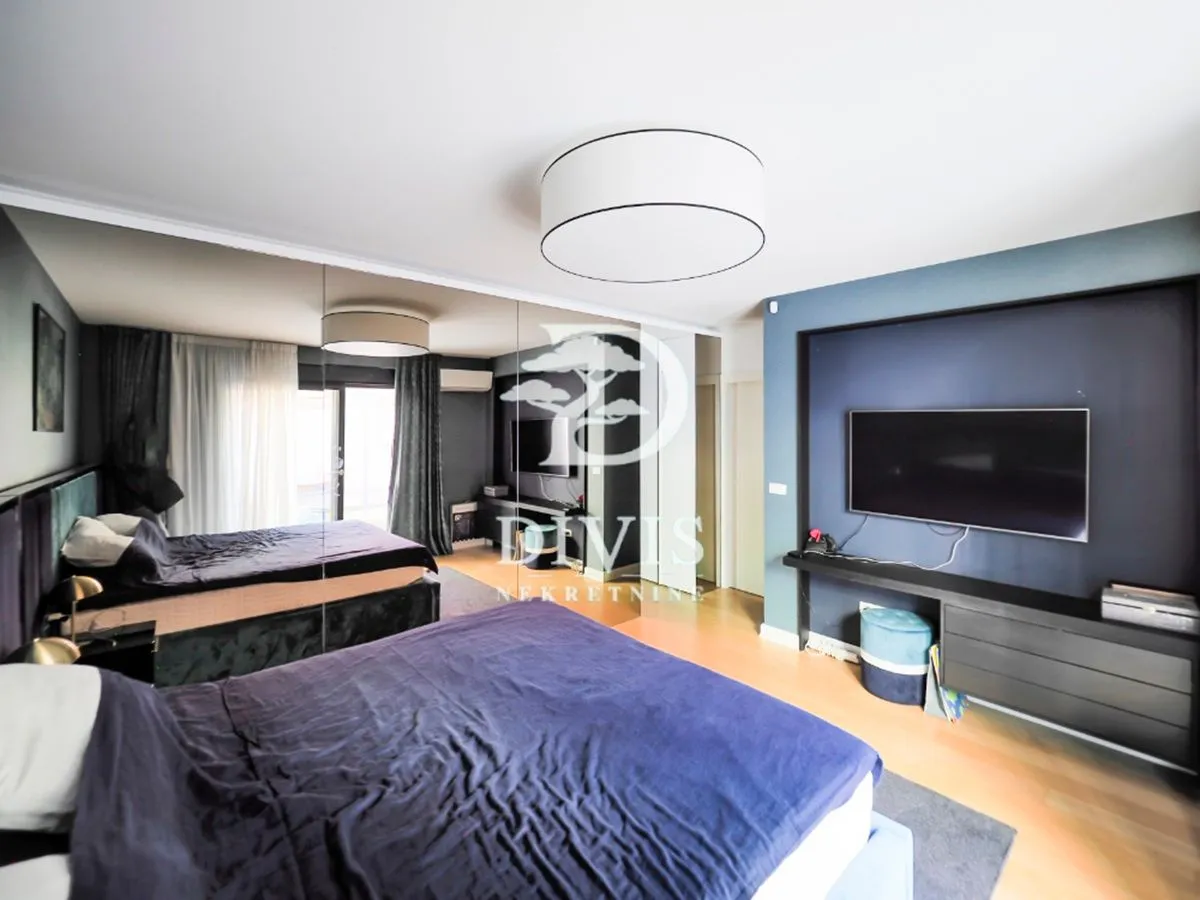 Spacious bedroom with a double bed, mirrored wardrobe, and a wall-mounted TV.