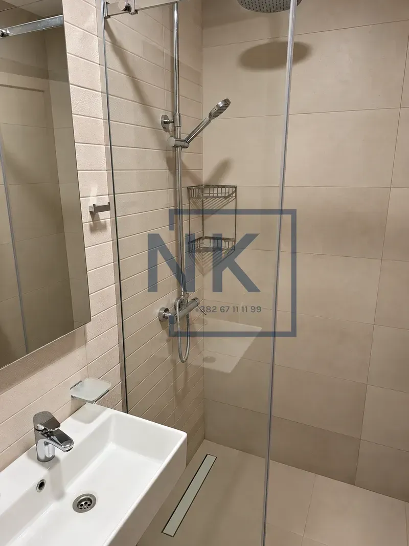 Modern bathroom with a walk-in shower and washbasin.