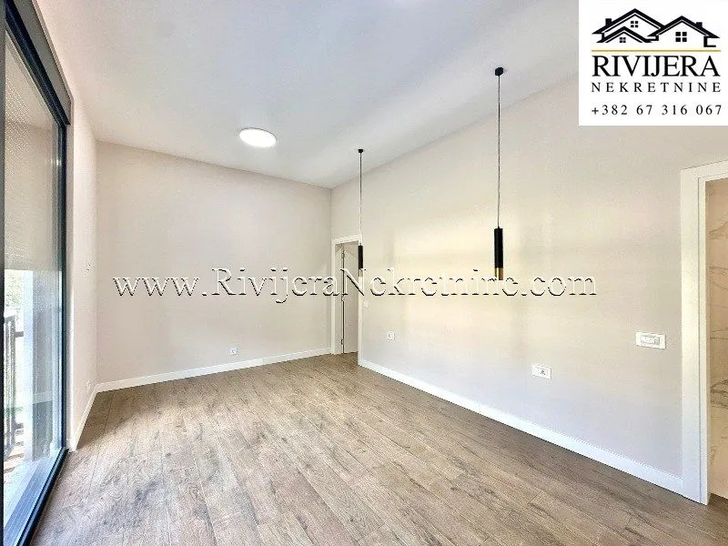 Empty room with wooden flooring, light walls, and pendant lamps.