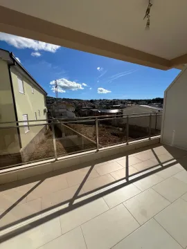 Empty tiled balcony with a glass railing and a view of the neighborhood. - image 9