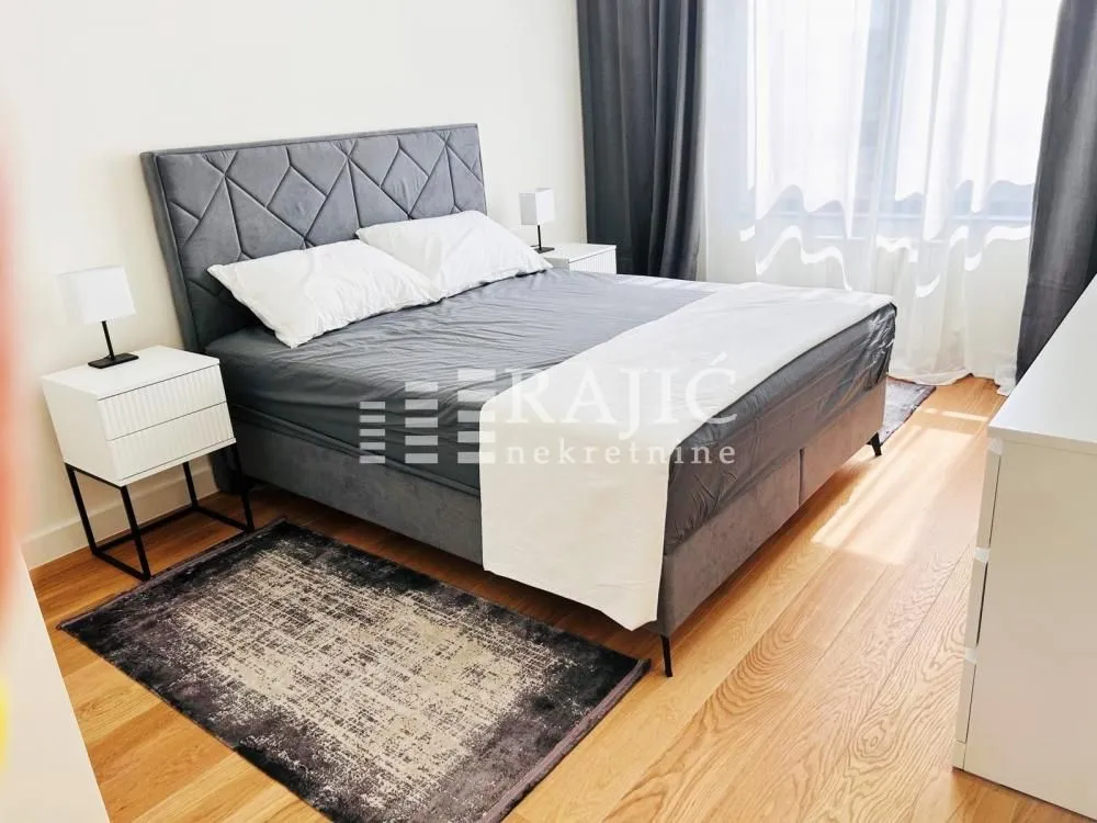 Modern bedroom with a double bed, bedside tables and wooden flooring.