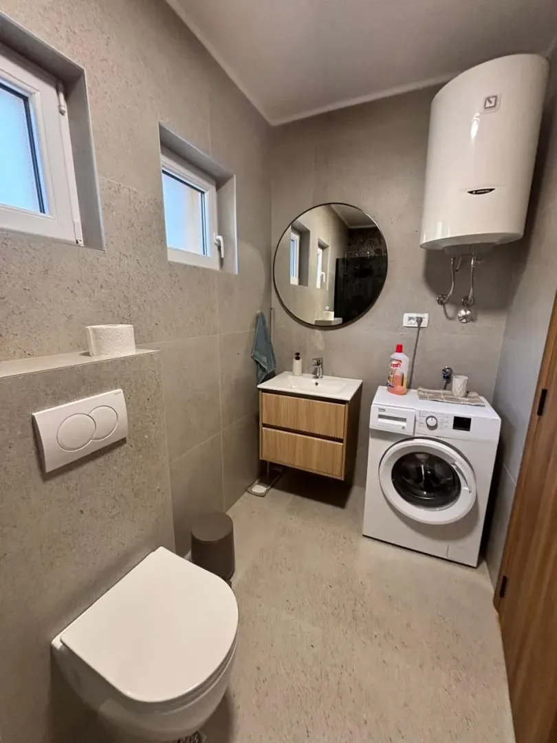 Modern equipped bathroom with a washing machine and water heater.