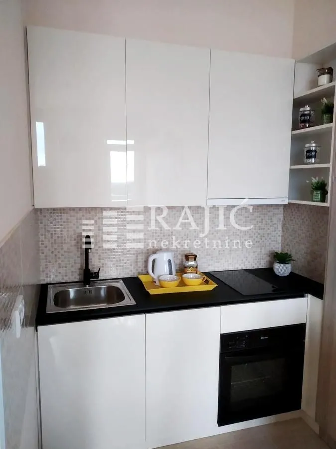 Small modern kitchen with white cabinets and a built-in oven.