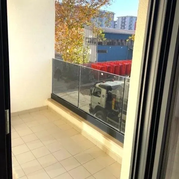 Small empty balcony with a glass railing and a view of the surroundings.