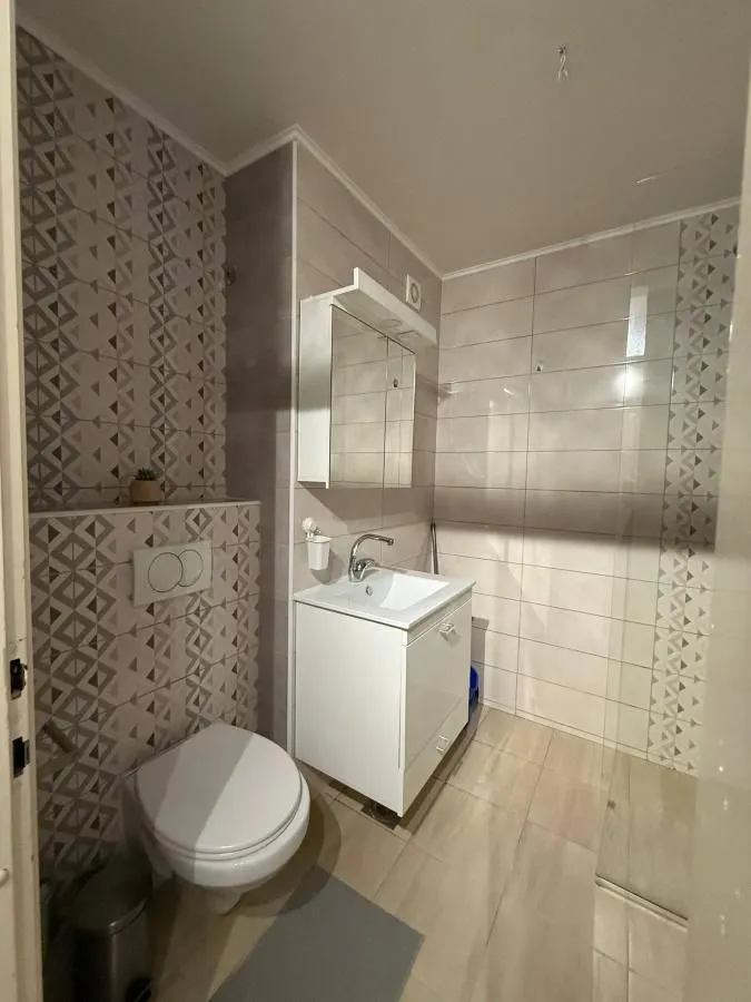 Moderno kupatilo sa umivaonikom, ogledalom i WC šoljom.