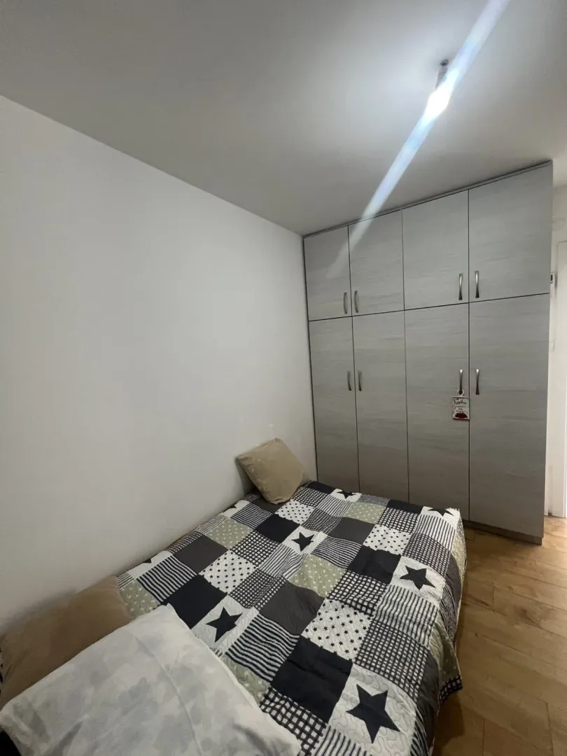 A simply furnished bedroom featuring a bed and a large built-in wardrobe.