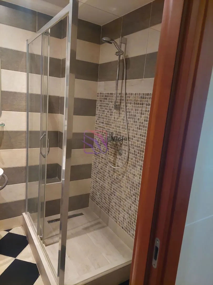 Bathroom with a shower cabin and mosaic wall tiles.