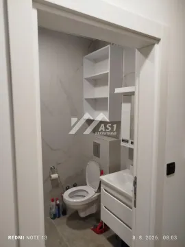Manje kupatilo sa WC šoljom, umivaonikom i belim policama. - image 3