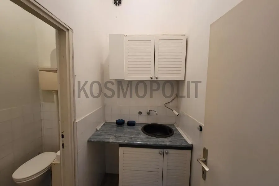 Small kitchen with a sink and wall cabinets next to the bathroom.