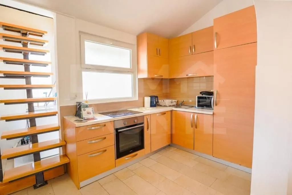 Kitchen with wooden cabinetry and a staircase in the corner.