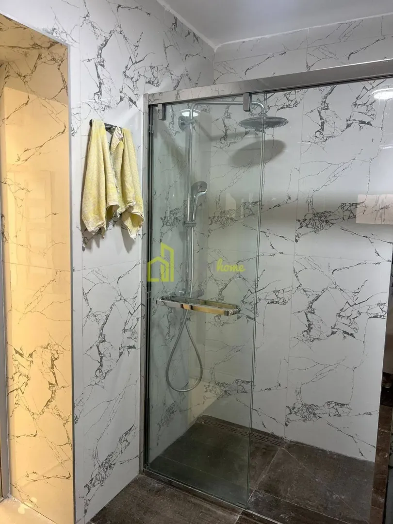 Modern bathroom with a walk-in shower and marble-look tiles.