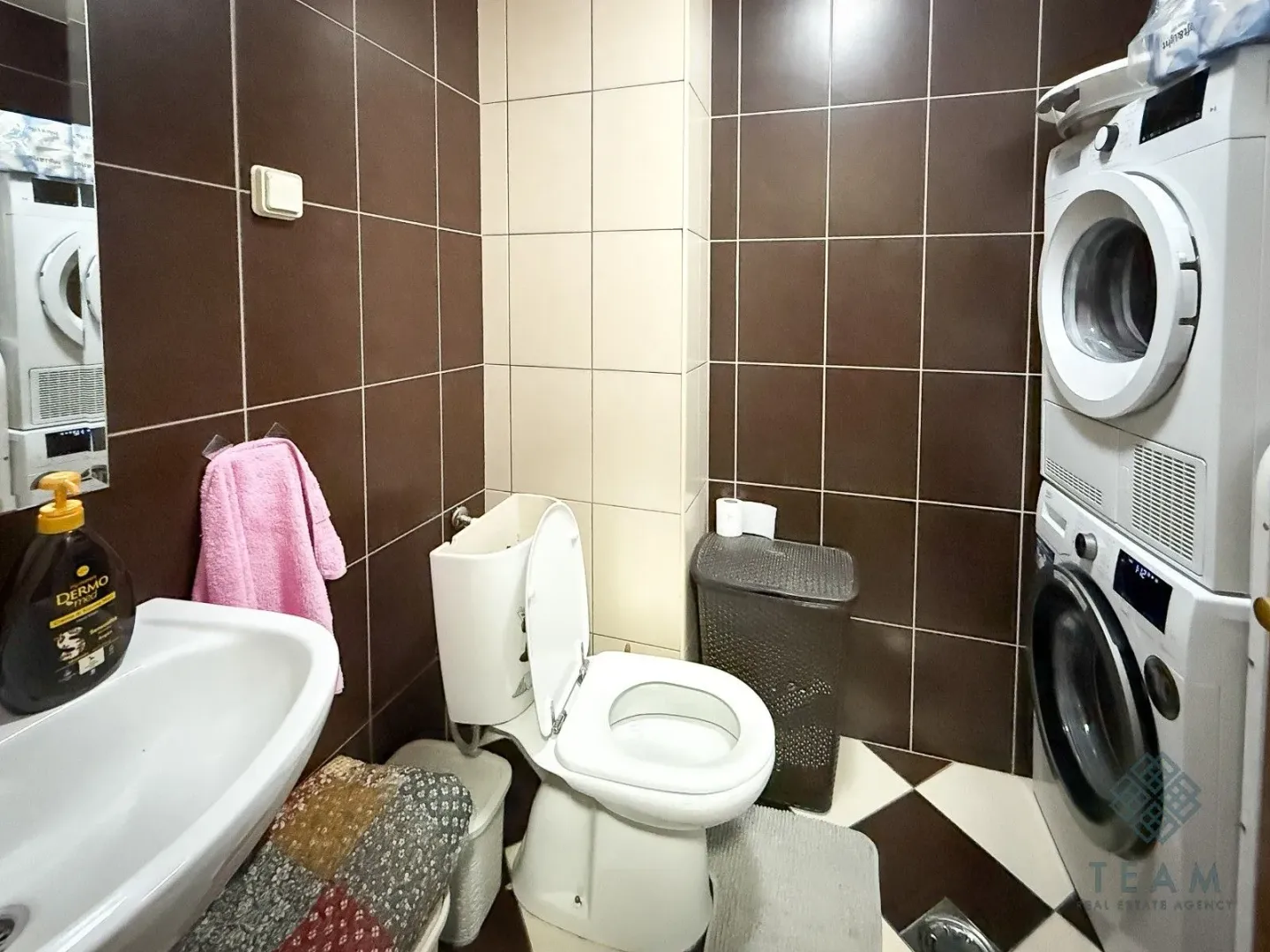 Kupatilo opremljeno umivaonikom, WC šoljom i veš mašinom.