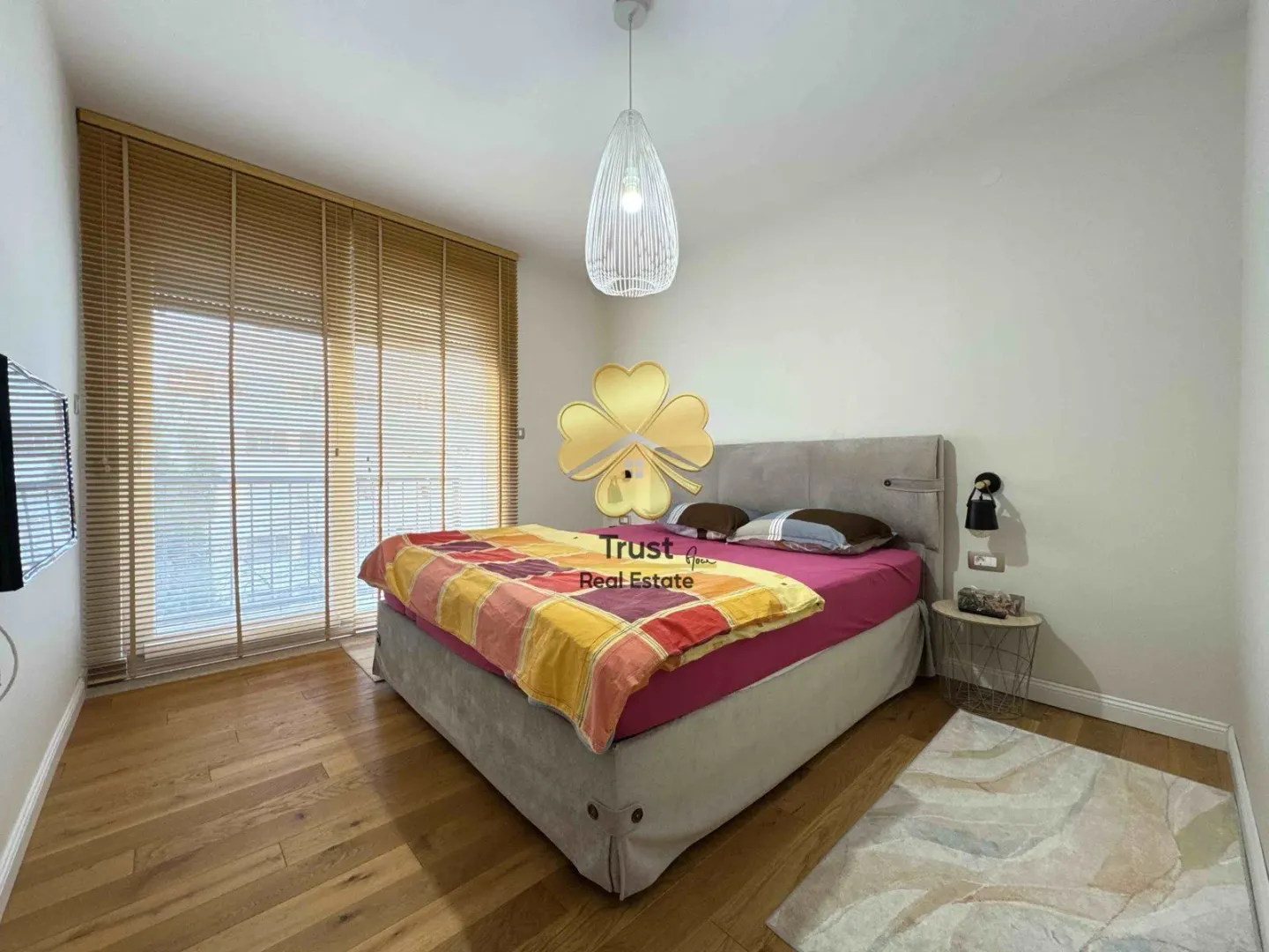Furnished bedroom with a double bed and wooden flooring.