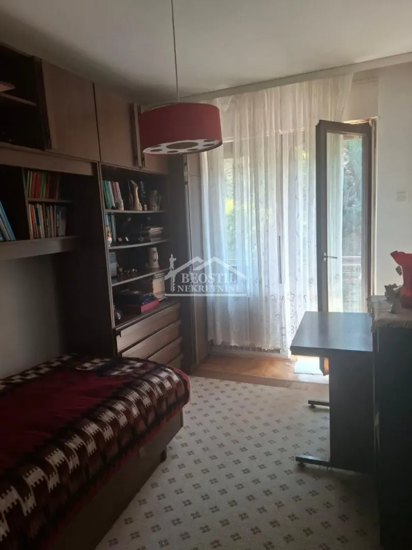 Nameštena spavaća soba sa krevetom, garderoberom i izlazom na terasu.