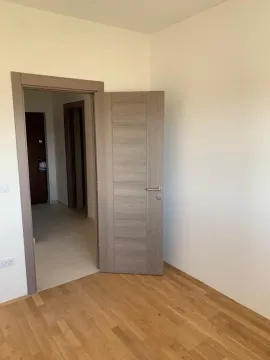 Prazna soba sa drvenim podom i otvorenim vratima koja vode u hodnik. - image 5