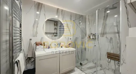 Modern bathroom equipped with marble tiles, a vanity with a sink, and a glass shower cabin. - image 6