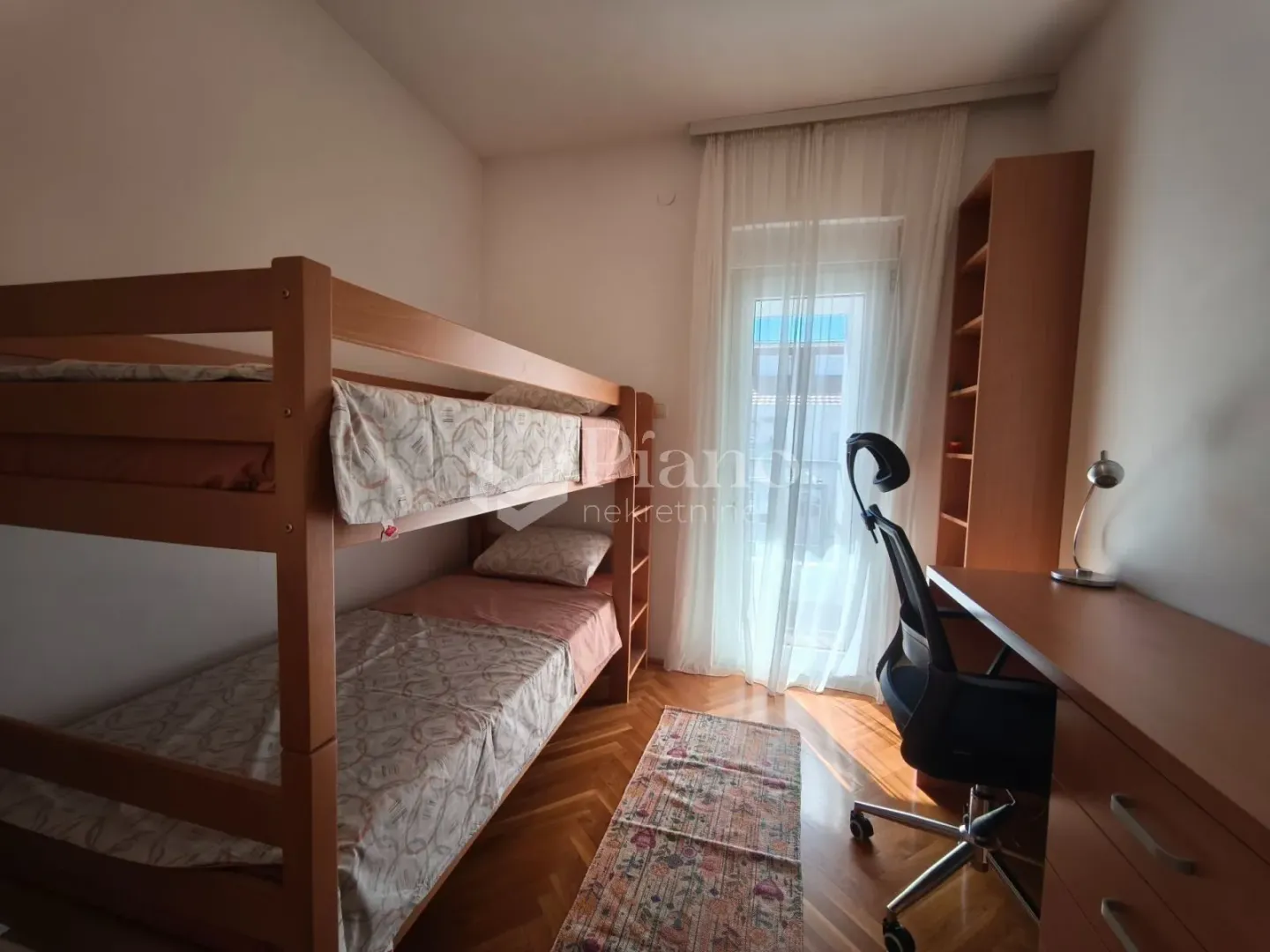 Dječja soba sa krevetom na sprat, radnim stolom i izlazom na terasu.