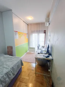 Smaller bedroom with a bed, a large wardrobe, and a desk by the window. - image 7