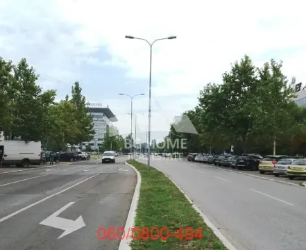 View of the street and parking area in front of the building with surrounding greenery. - image 3
