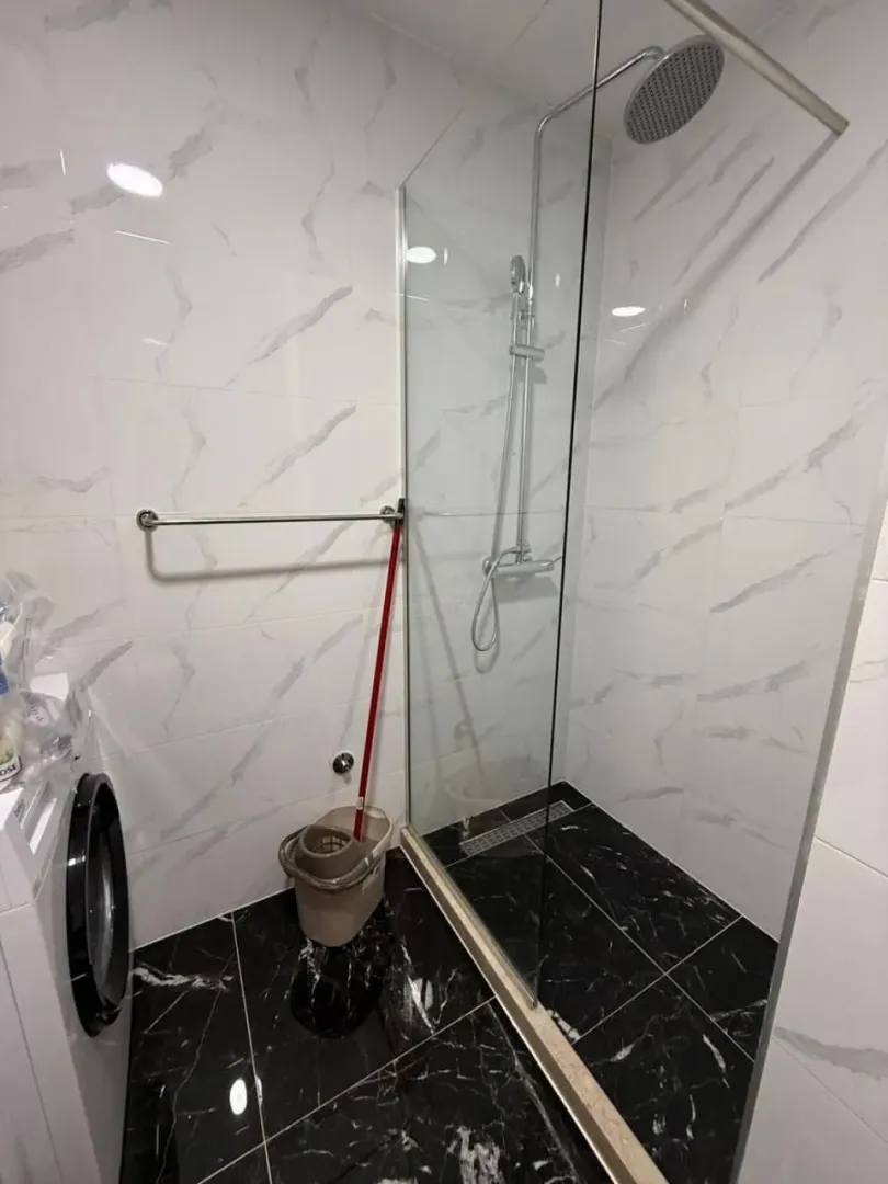 Moderne kupatilo sa tuš kabinom i crno-bijelim pločicama.